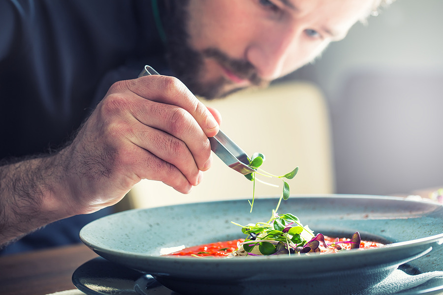 A chef adding a touch of herbs to an entree.
